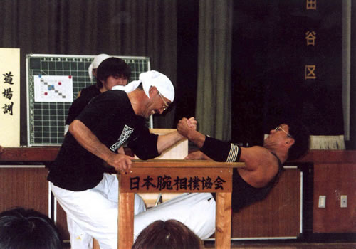 比田井 高廣さん（左で腕相撲を取っているタオルをまいている側）